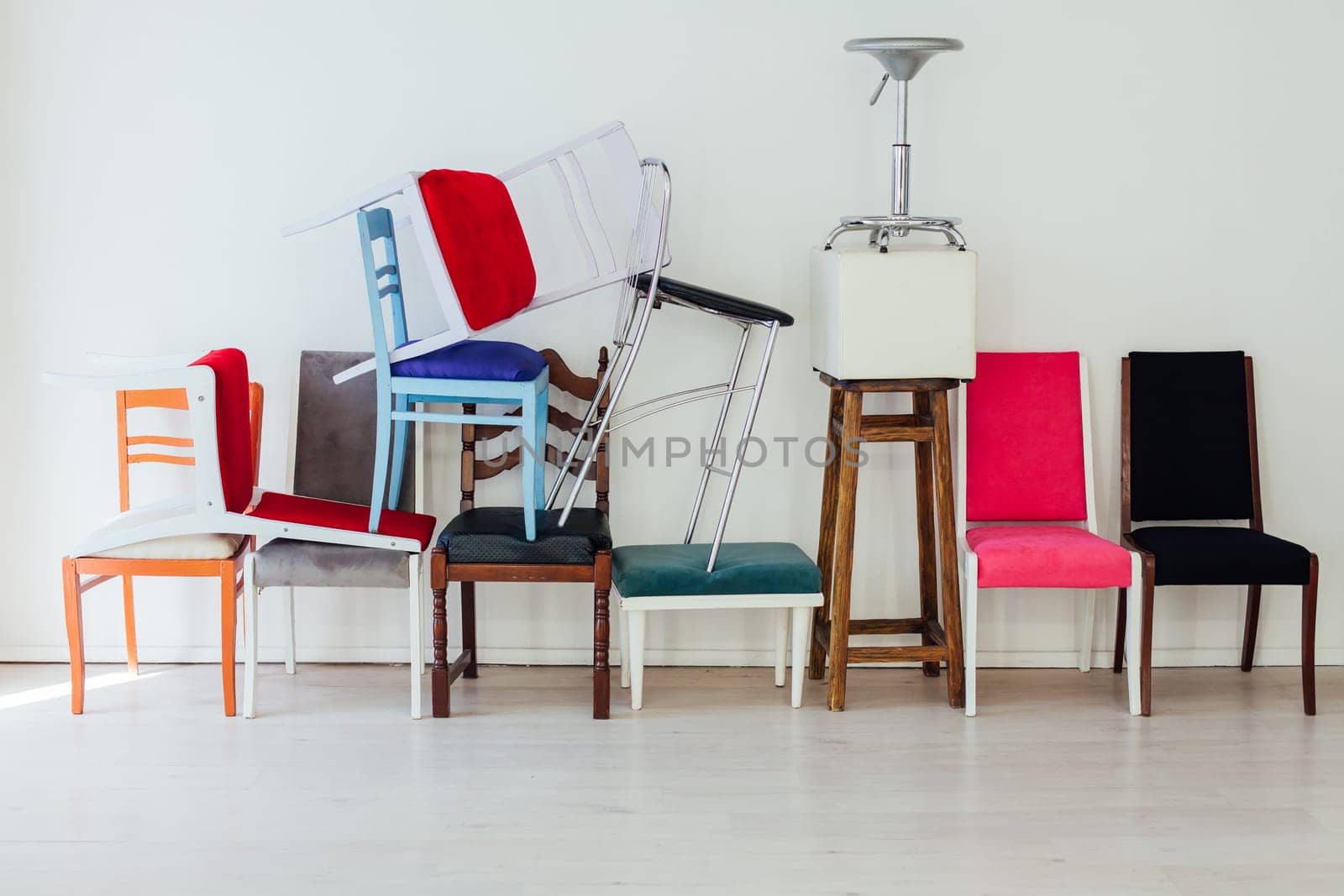 many different chairs in disarray in the interior of an empty white room