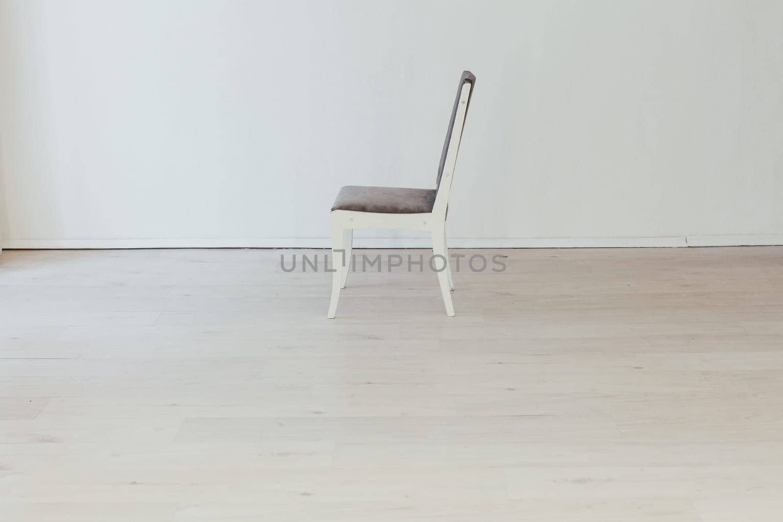 gray chair in the interior of an empty white room by Simakov