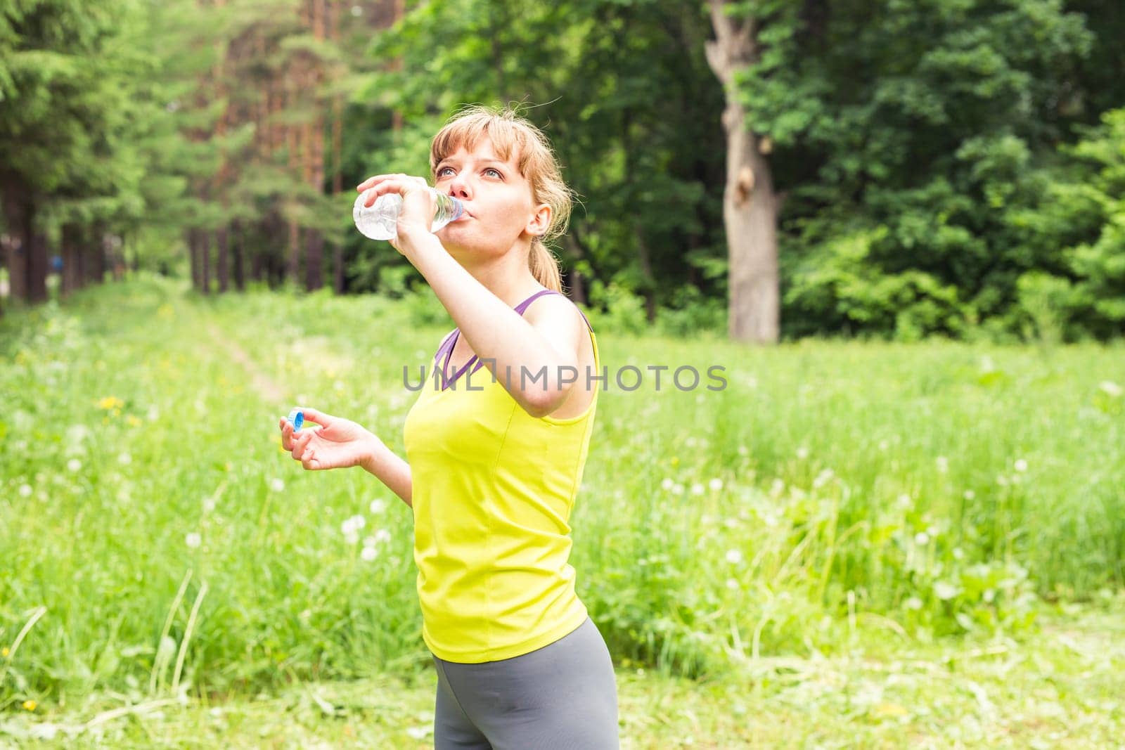 Young woman drinking water from plastic bottles after jogging. Lose weight. Healthy lifestyle. by Satura86