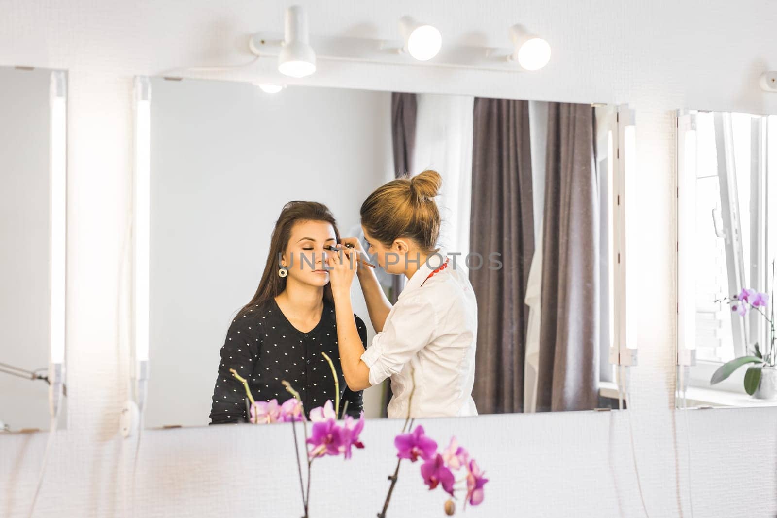 Make-up artist doing make up for young beautiful bride applying wedding make-up