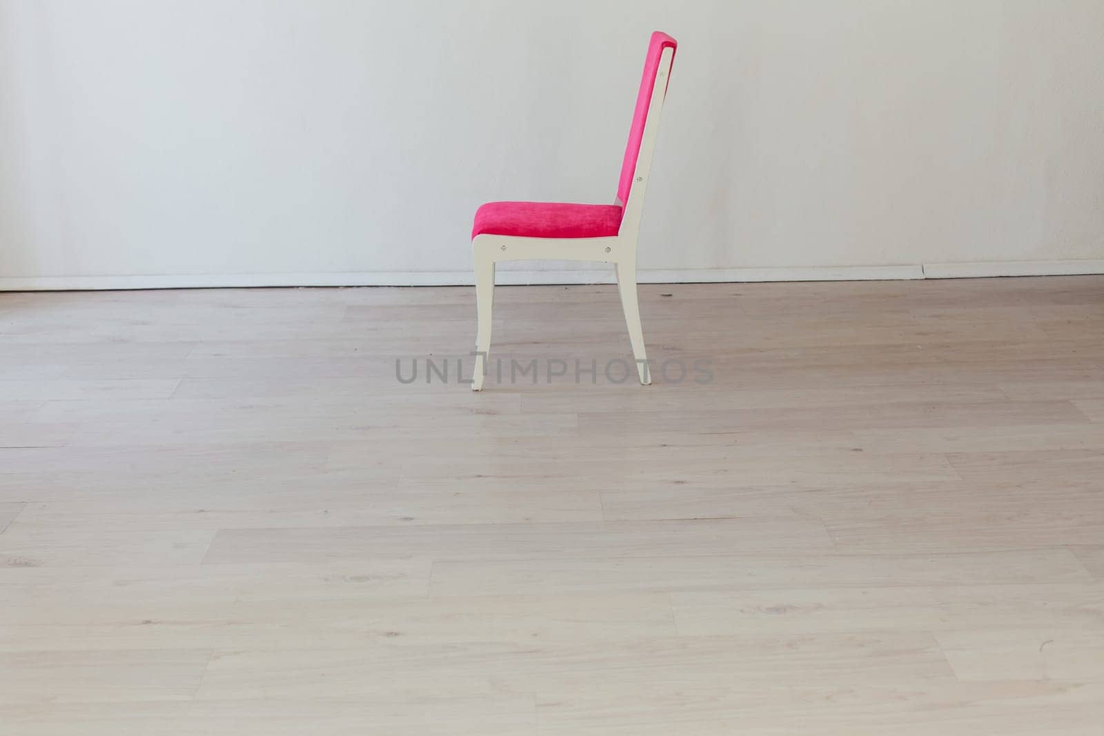 pink chair in the interior of an empty white room by Simakov