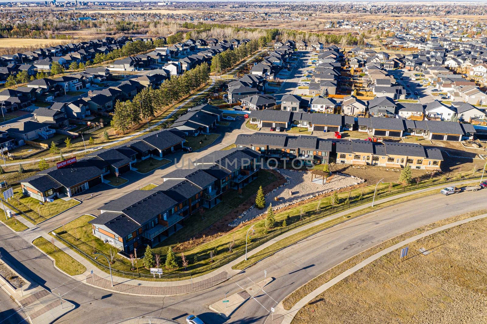 Aerial image of Evergreen, Saskatoon, SK, highlighting tree-lined streets, modern homes, and green spaces. A serene neighborhood portrait, ideal for real estate and urban planning.