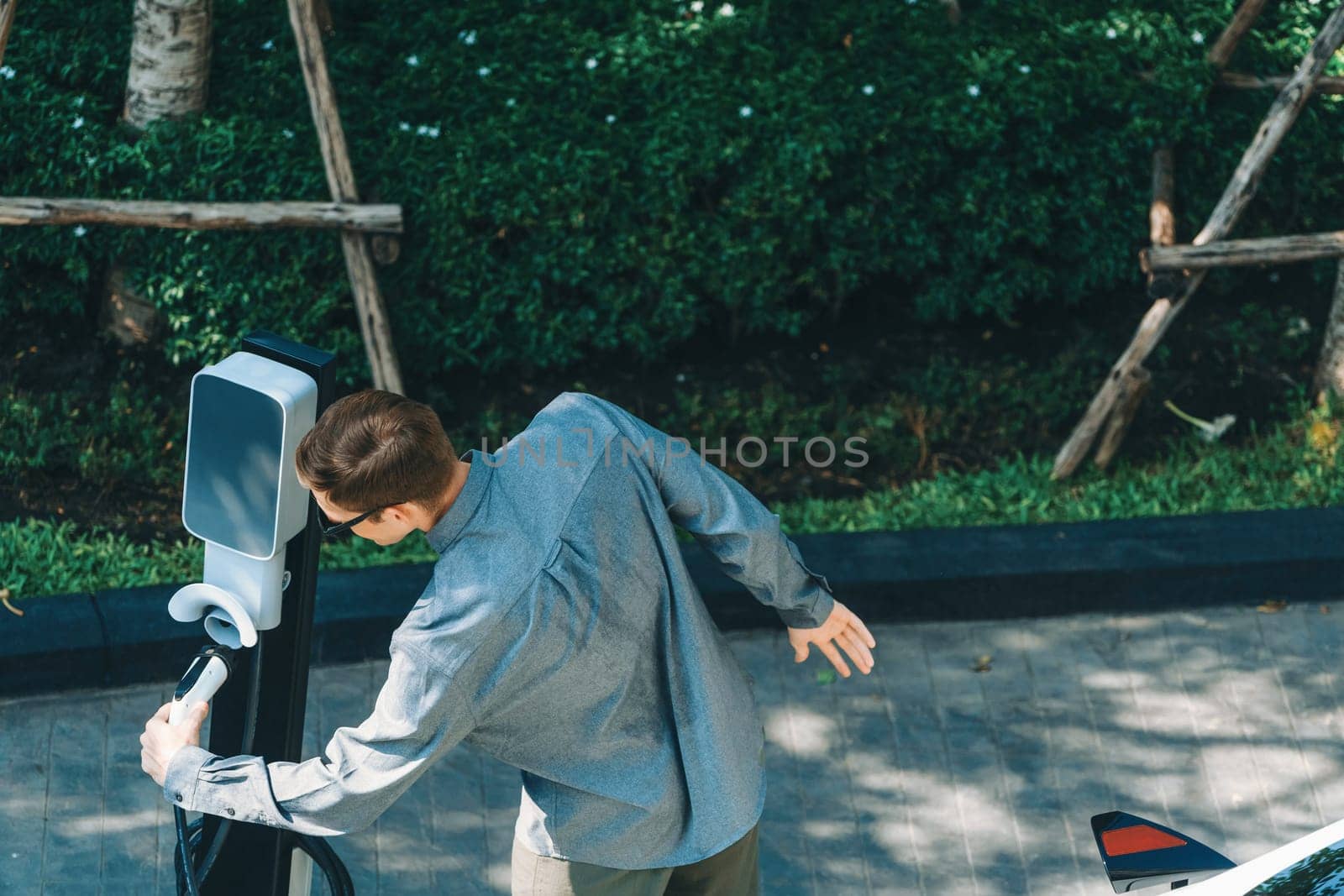 Young man travel with EV electric car in green sustainable city innards by biancoblue