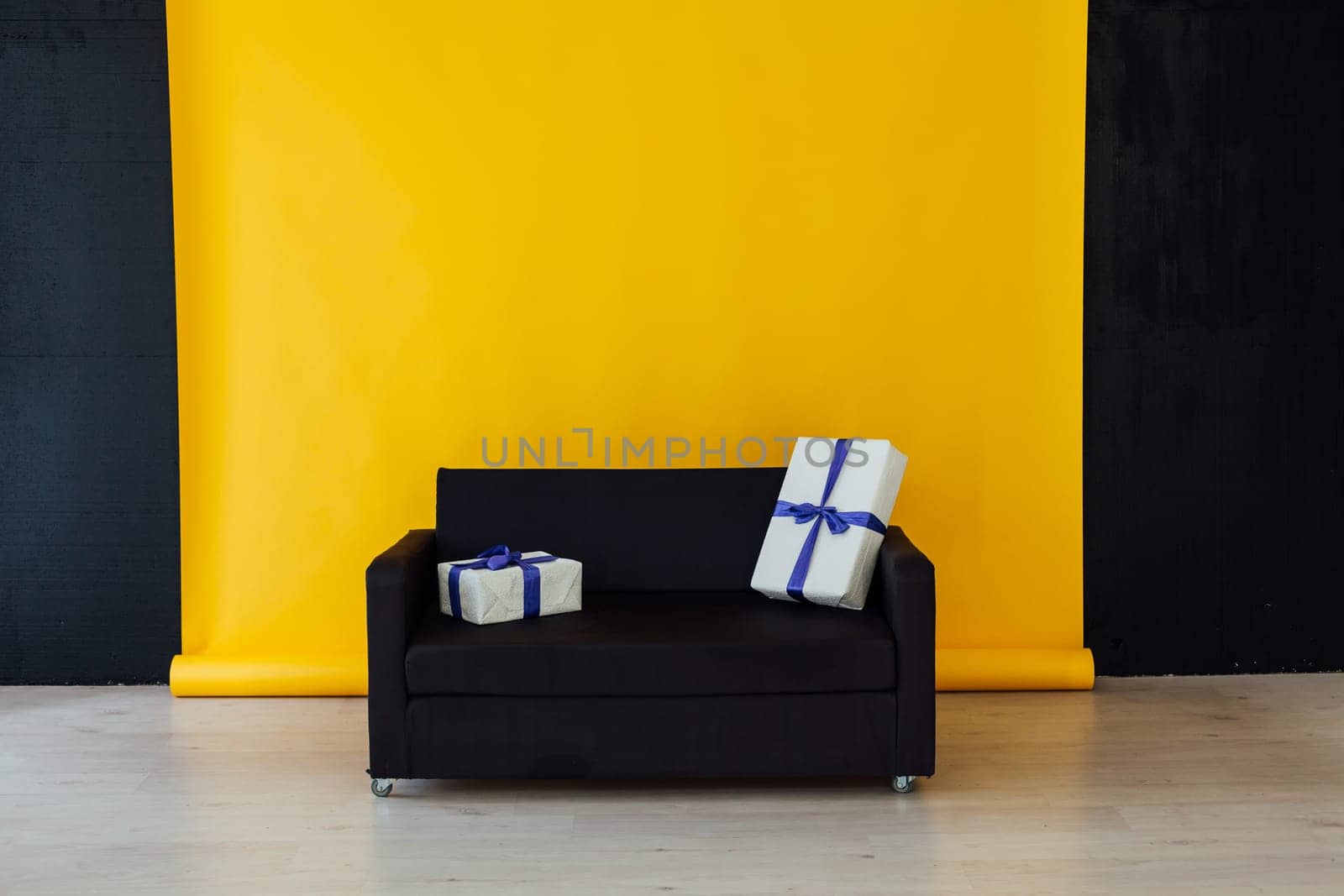 black sofa with feasting gifts in the interior of the room with a yellow background