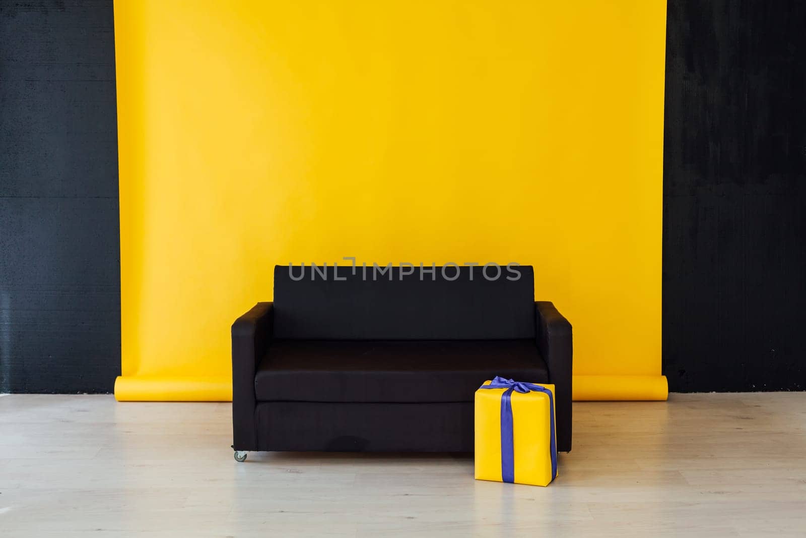 black sofa with feasting gifts in the interior of the room with a yellow background
