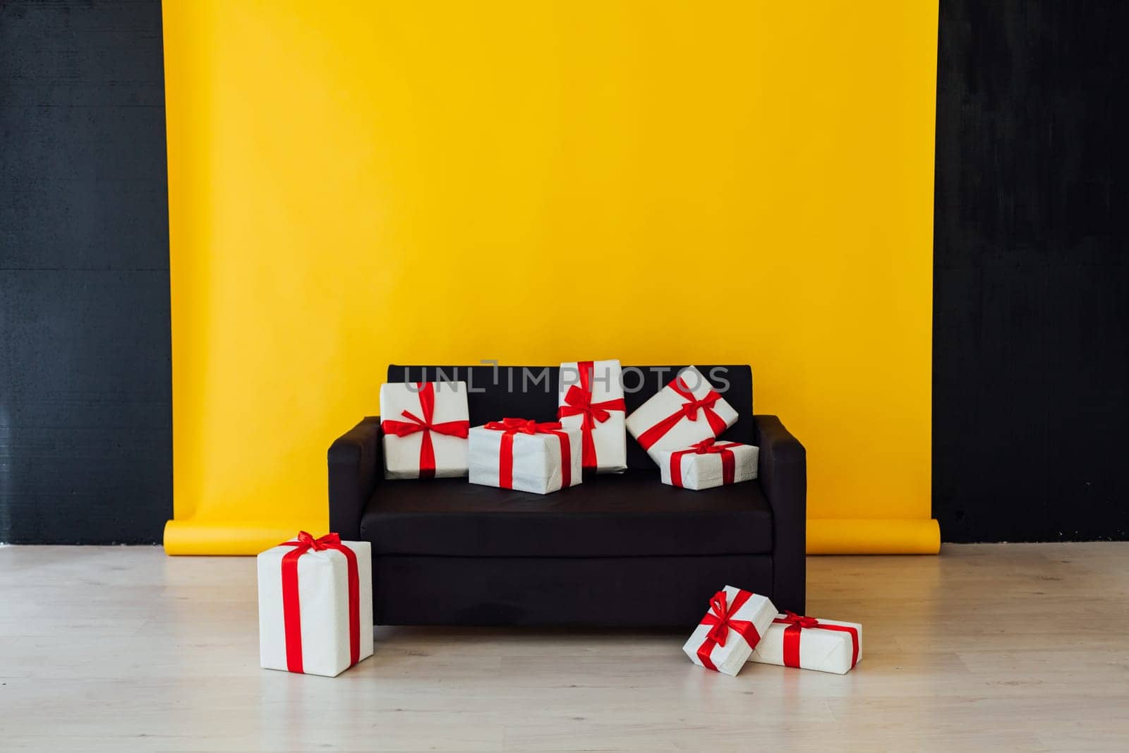 black sofa with gifts in the interior of the room with a yellow background by Simakov