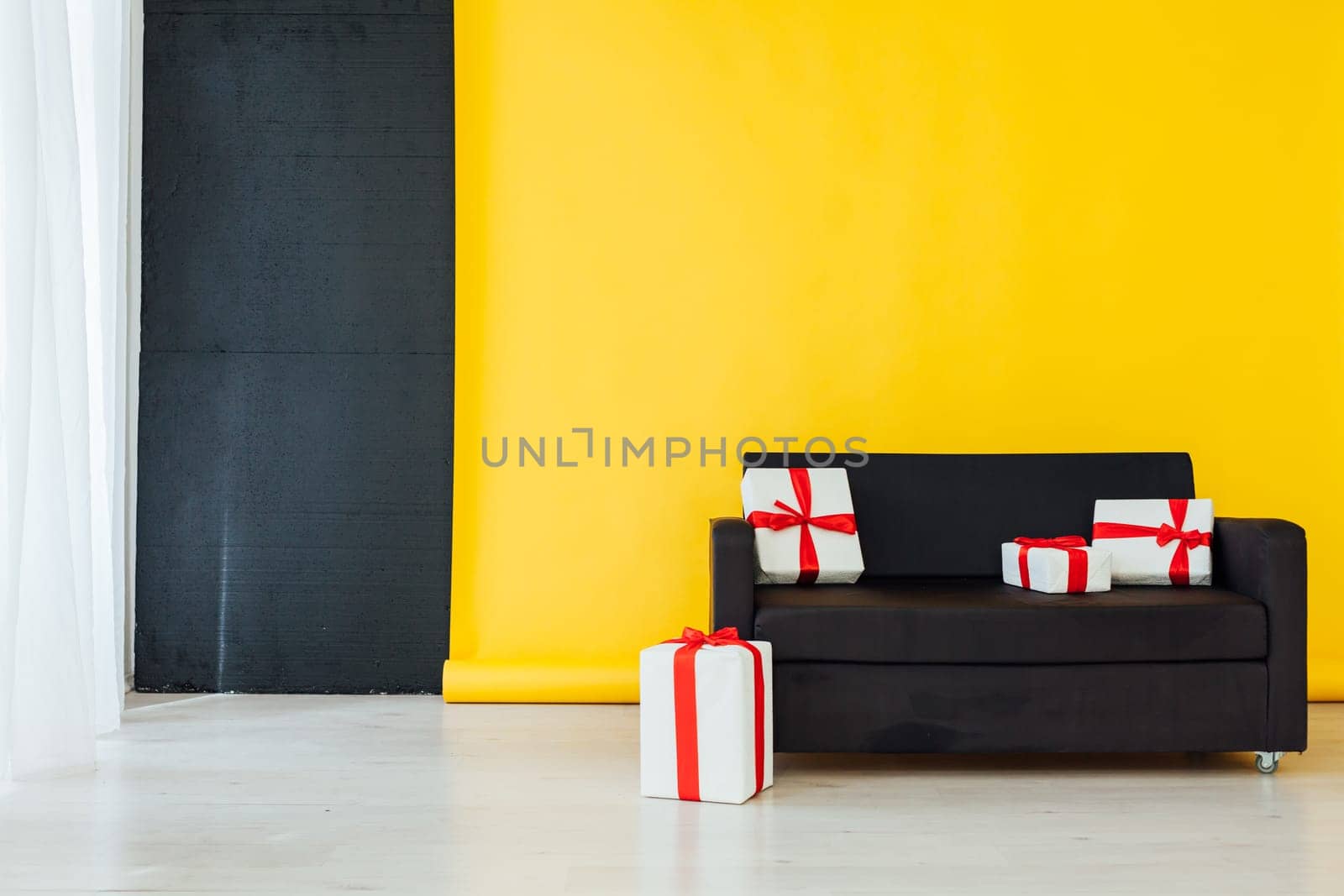 black sofa with gifts in the interior of the room with a yellow background by Simakov
