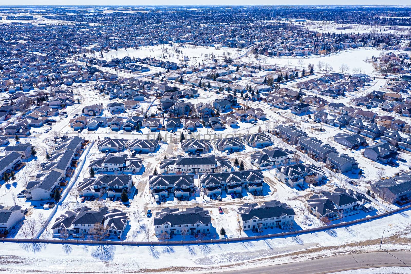 Aerial image of Evergreen, Saskatoon, SK, highlighting tree-lined streets, modern homes, and green spaces. A serene neighborhood portrait, ideal for real estate and urban planning.