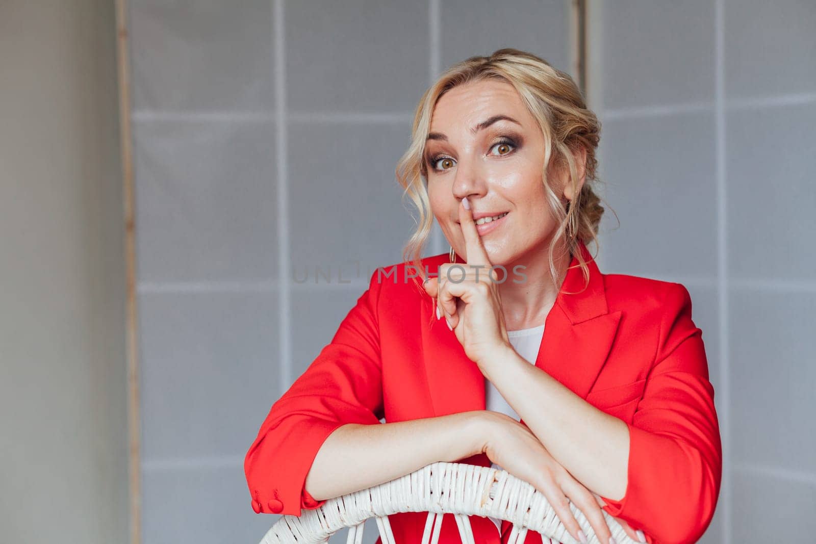 Portrait of a beautiful blonde woman in a red business suit in the office by Simakov