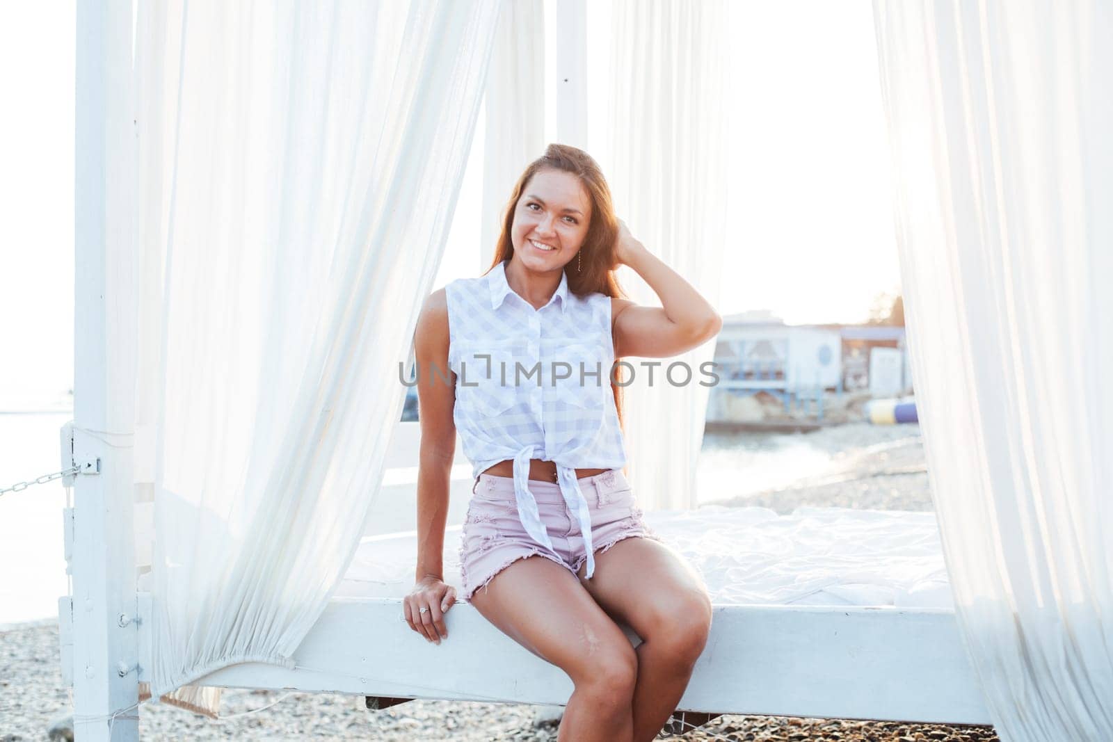 Beautiful tanned woman portrait at dawn on the beach by Simakov