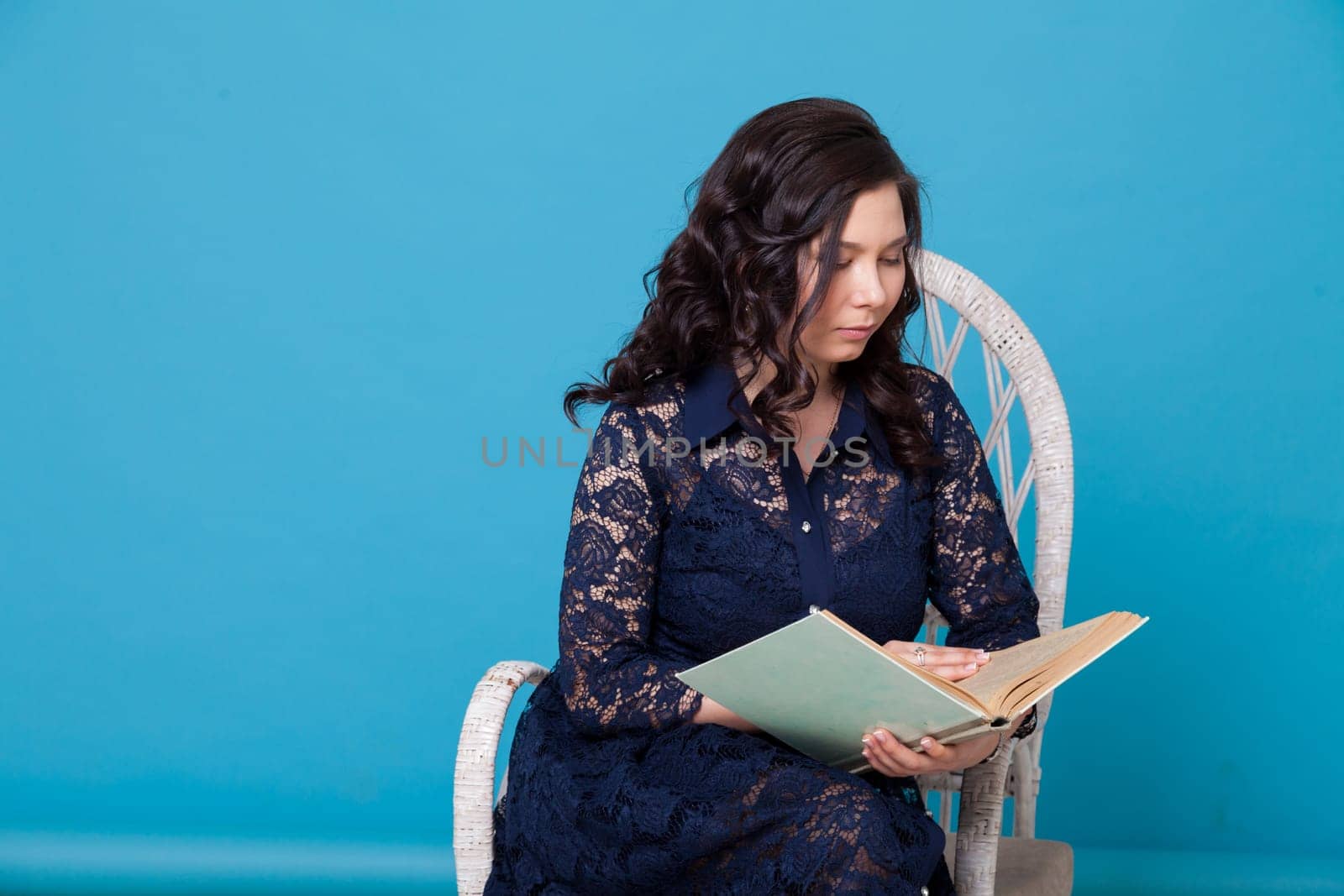 Portrait of a beautiful Asian woman reads a book on a blue background