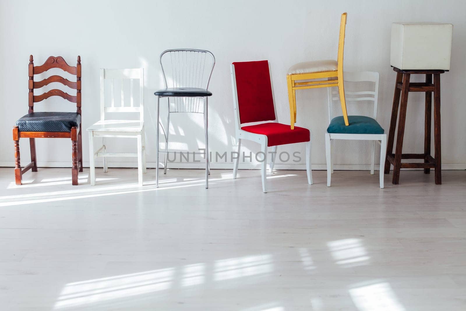 many multicolored chairs in the mess of the white room by Simakov