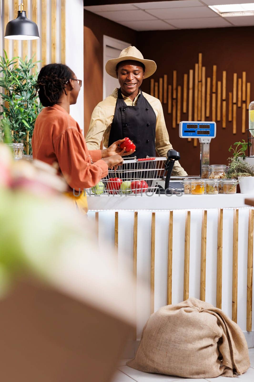 Black woman receives warm assistance from a male vendor while shopping for fresh fruits. The shopkeeper offers variety of vibrant and healthy fruit options, creating positive shopping experience.