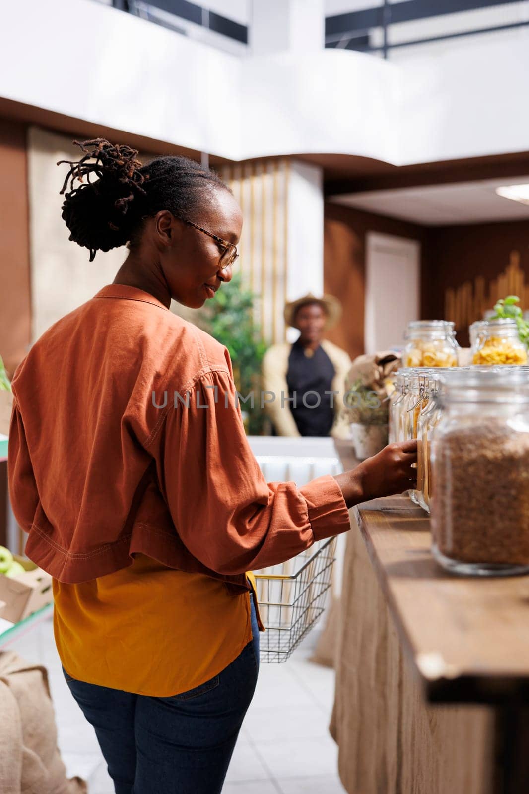 African American client shops for fresh, locally grown produce in a grocery store. They verify organic options and explore eco friendly packaging. The store offers sustainable, zero waste choices for a healthy, conscious shopping experience.