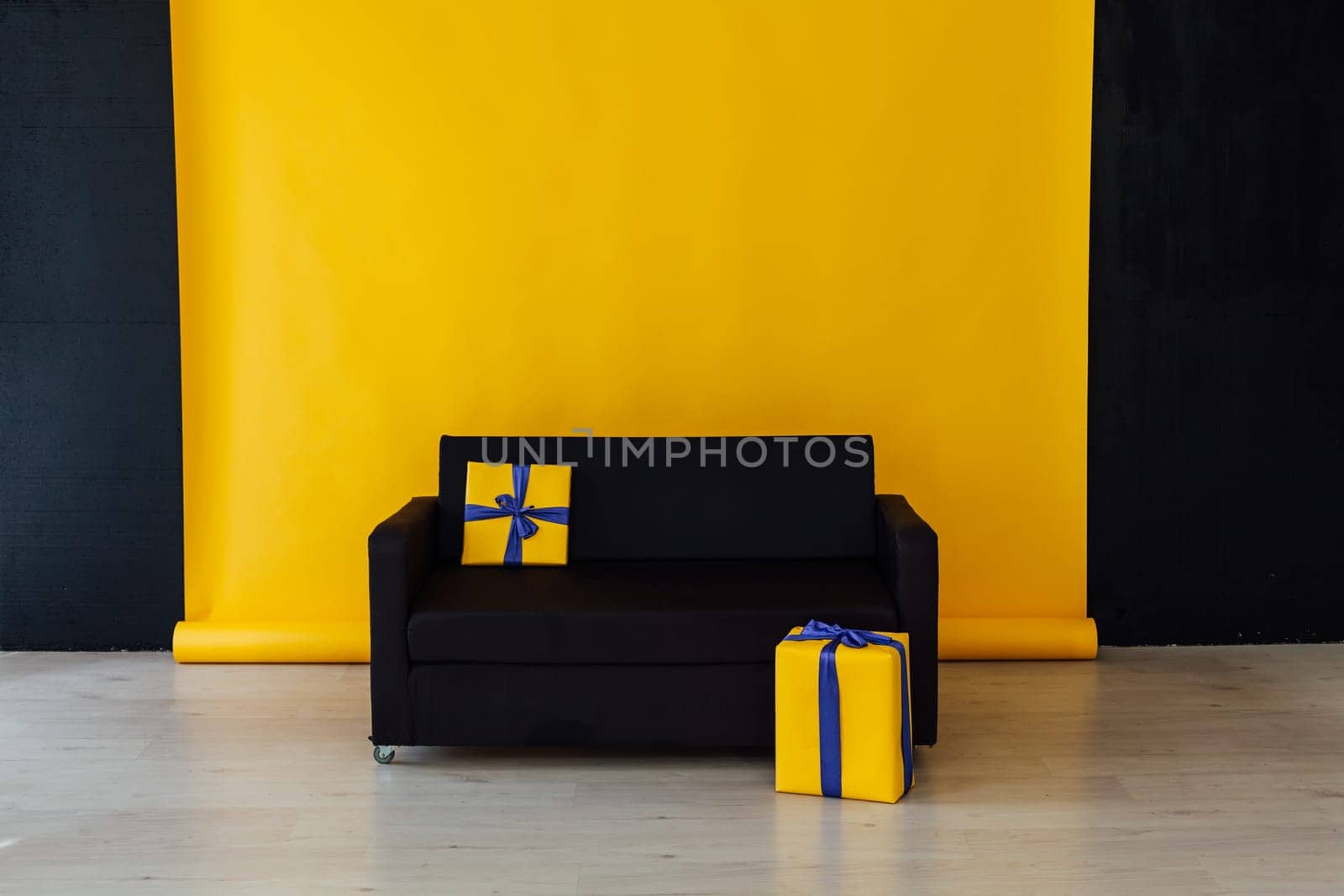 black sofa with a gift in the interior of the room with a yellow background by Simakov