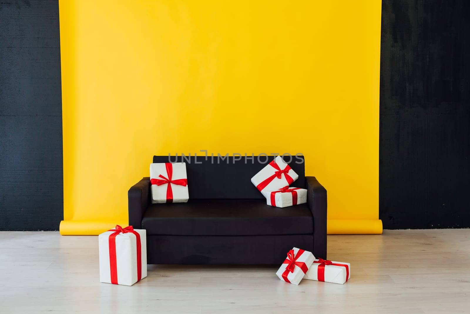 black sofa with a gift in the interior of the room with a yellow background by Simakov