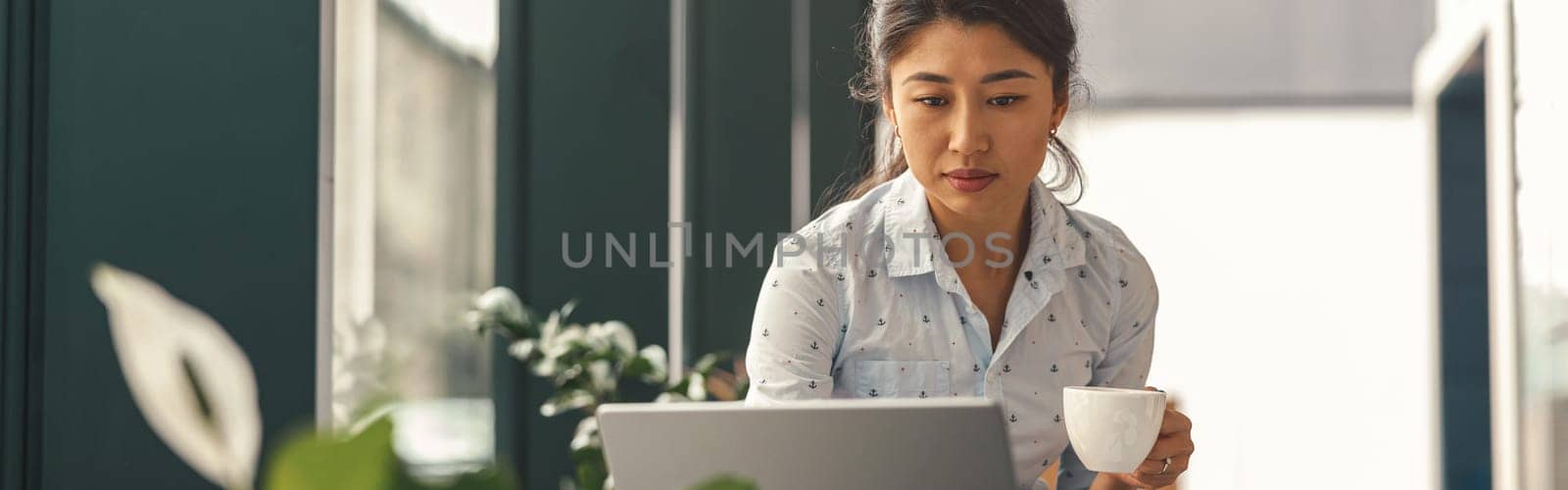 Female entrepreneur working on laptop while sitting the desk in modern coworking. High quality photo