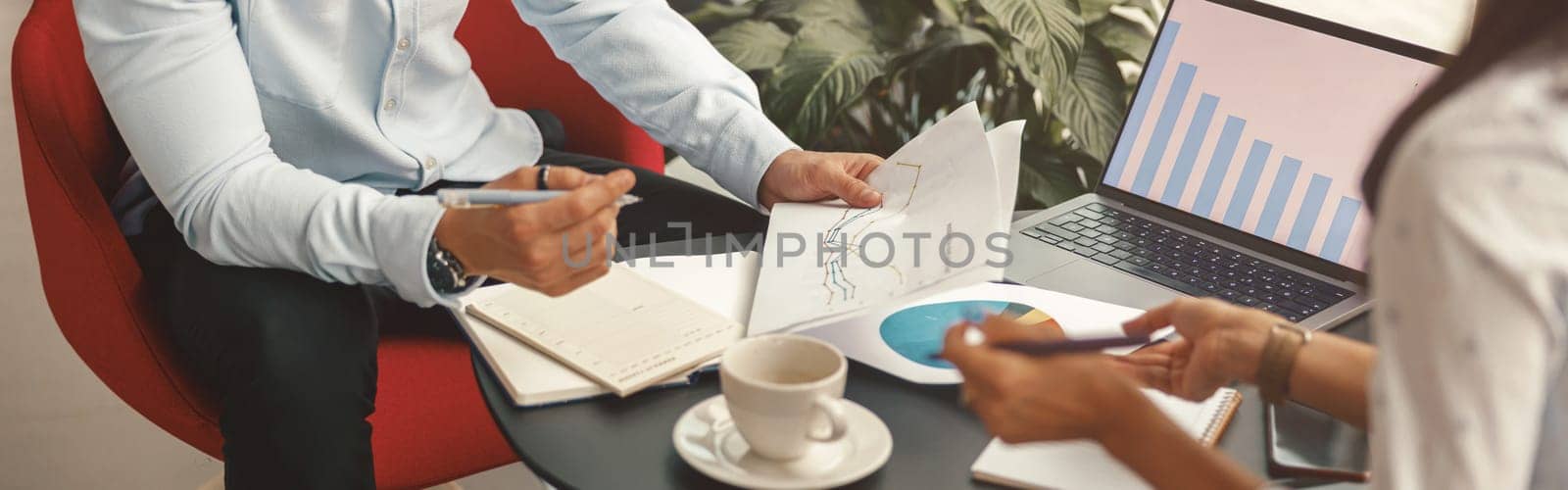 Close up of business colleagues working together with financial statements in stylish meeting room by Yaroslav_astakhov