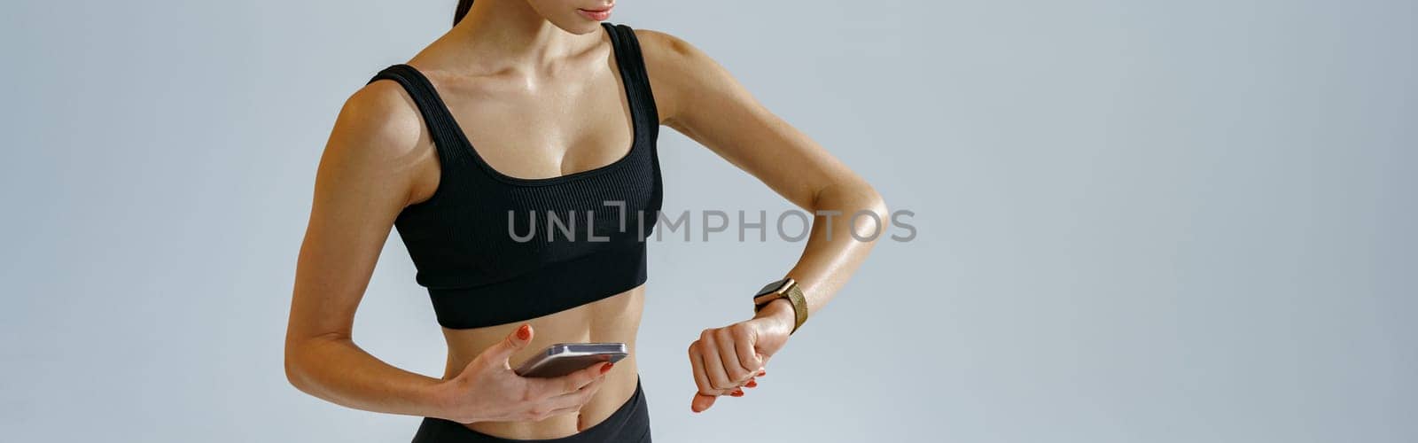Athletic woman checking her smartwatch after training over studio background. High quality photo