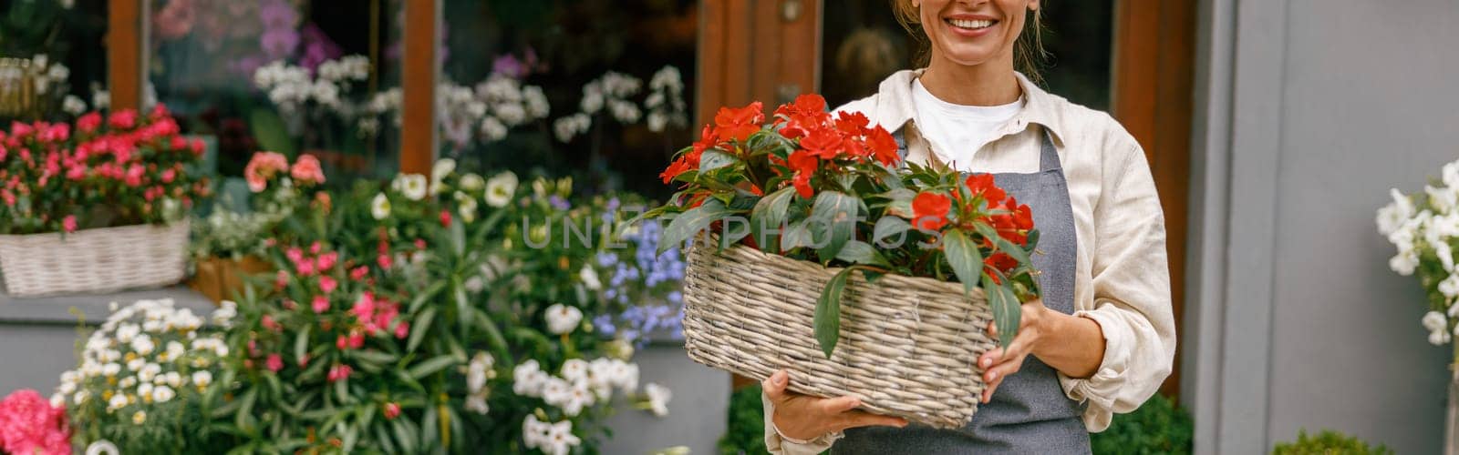 Woman florist small business owner standing in floral store and waiting for client with houseplant