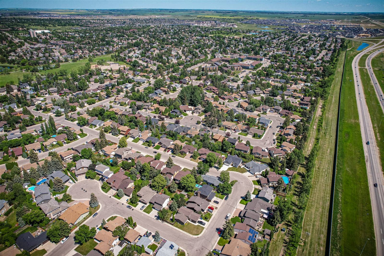 Soaring over Lakeview in Saskatoon, this bird's-eye capture magnifies the neighborhood's tranquil waters, verdant parks, and the serene rhythm of Saskatchewan living