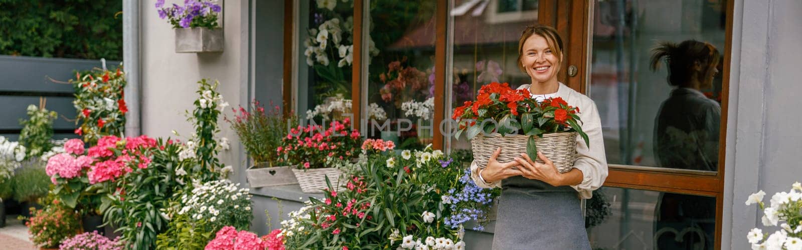 Woman florist small business owner standing in floral store and waiting for client with houseplants