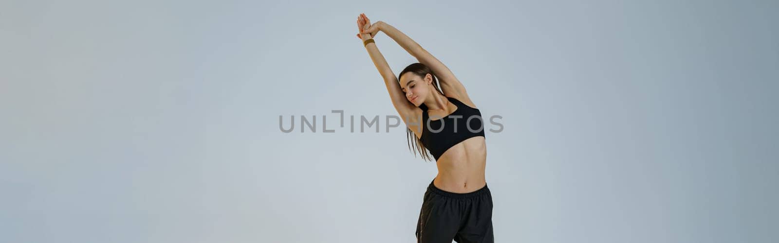 Athletic woman wearing sportswear doing warm-up before training session in gym on studio background by Yaroslav_astakhov