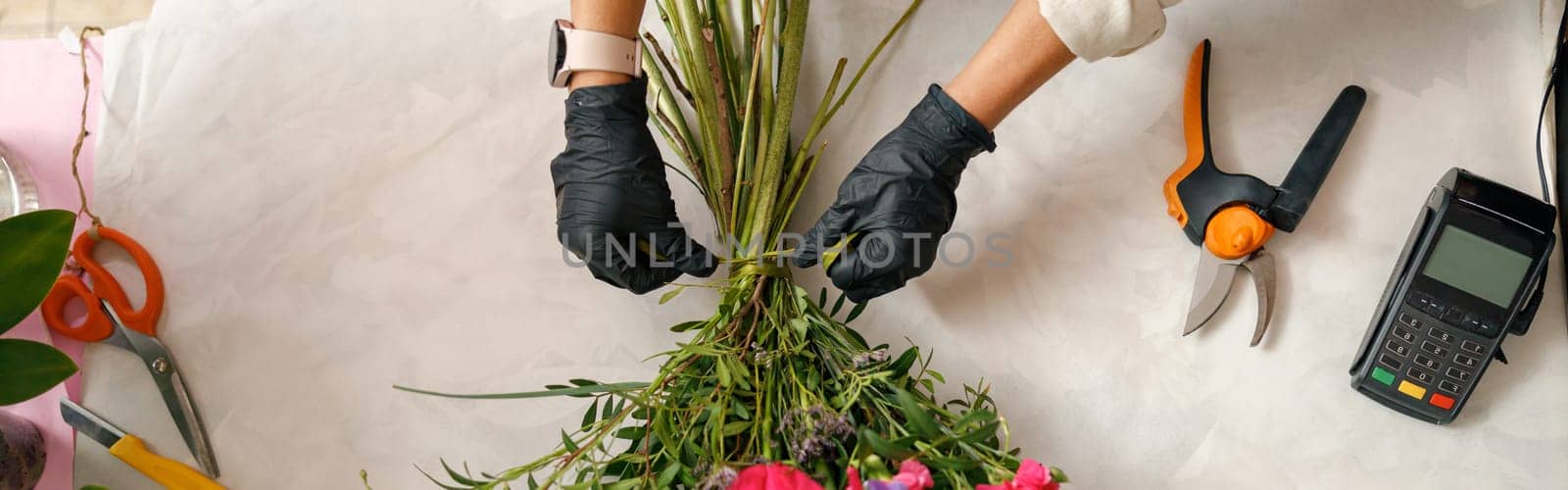 Close up of gardener's in the flower shop make bouquet for a holiday. Family flower's business