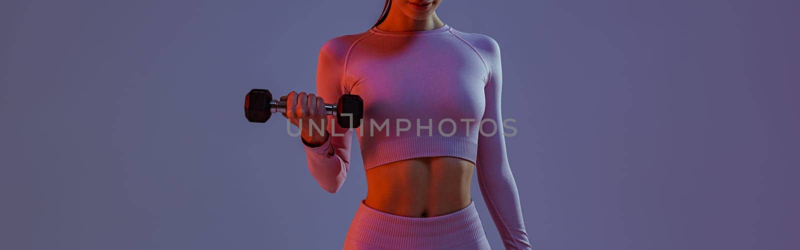 Woman doing exercises with dumbbells on studio background . Sport and healthy lifestyle