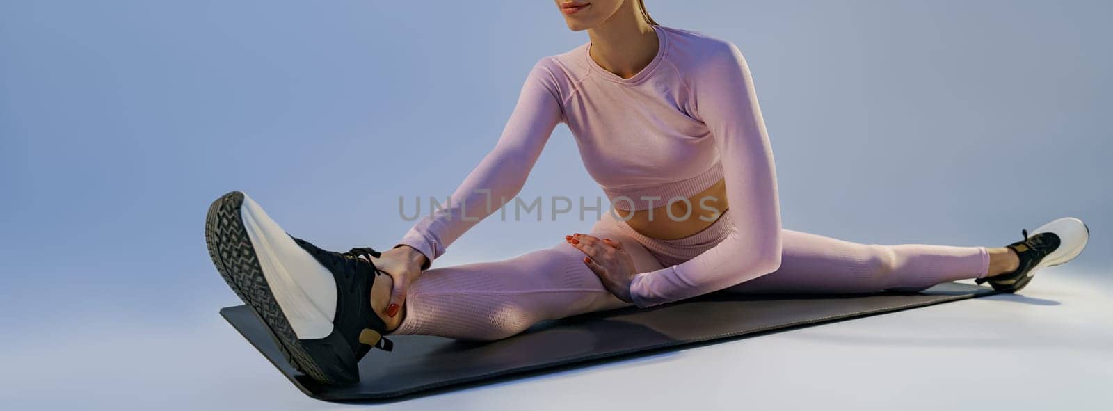 Sporty woman doing stretching exercises on yoga mat on studio background. Healthy lifestyle by Yaroslav_astakhov