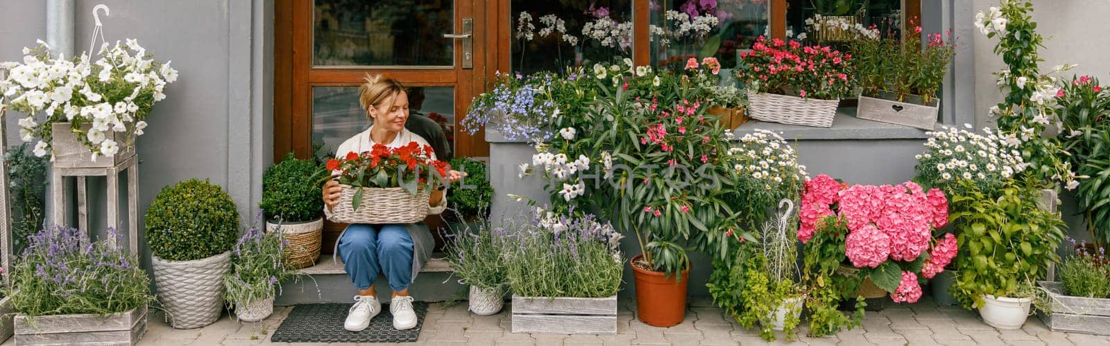 Woman florist small business owner sitting in floral store and waiting for client with houseplants