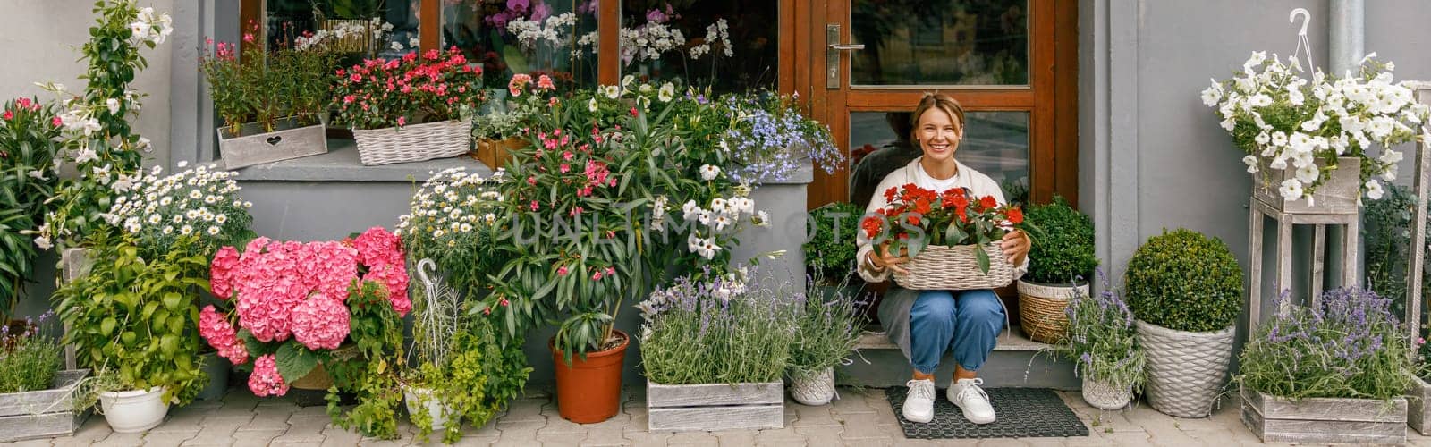 Smiling woman florist business owner sitting with houseplants on background of floral store by Yaroslav_astakhov