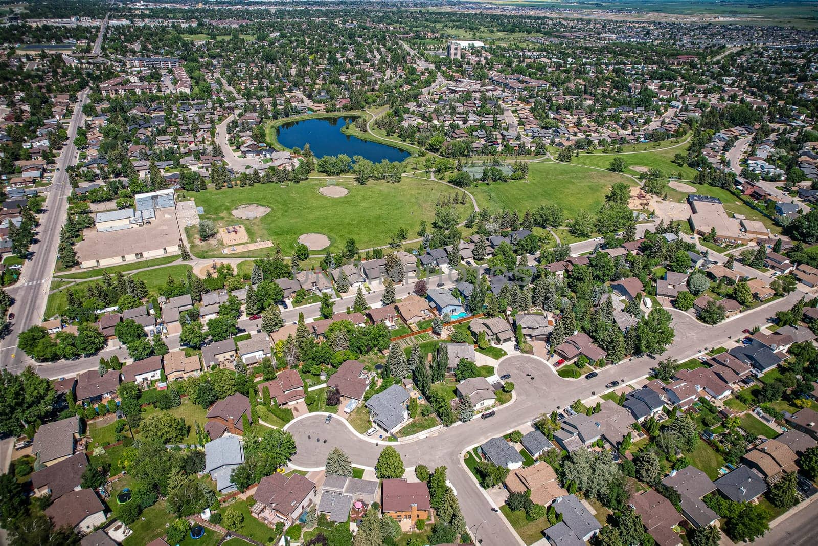 Soaring over Lakeview in Saskatoon, this bird's-eye capture magnifies the neighborhood's tranquil waters, verdant parks, and the serene rhythm of Saskatchewan living