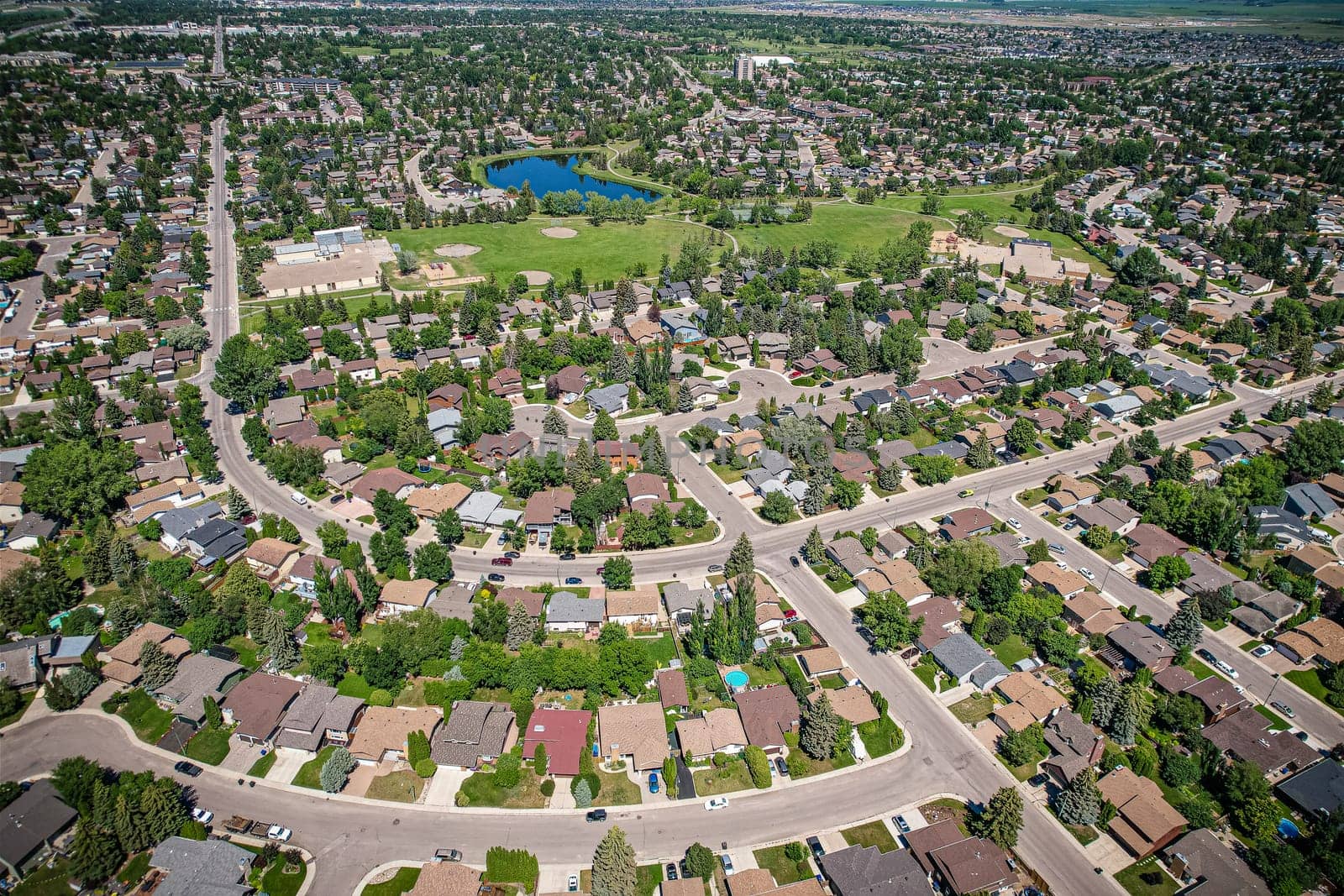 Soaring over Lakeview in Saskatoon, this bird's-eye capture magnifies the neighborhood's tranquil waters, verdant parks, and the serene rhythm of Saskatchewan living