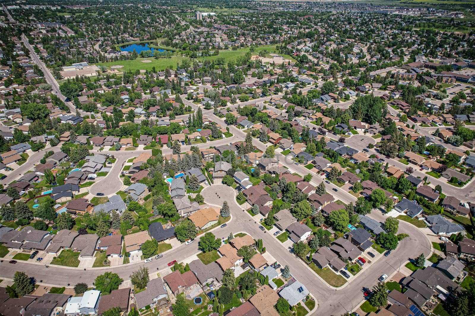 Soaring over Lakeview in Saskatoon, this bird's-eye capture magnifies the neighborhood's tranquil waters, verdant parks, and the serene rhythm of Saskatchewan living