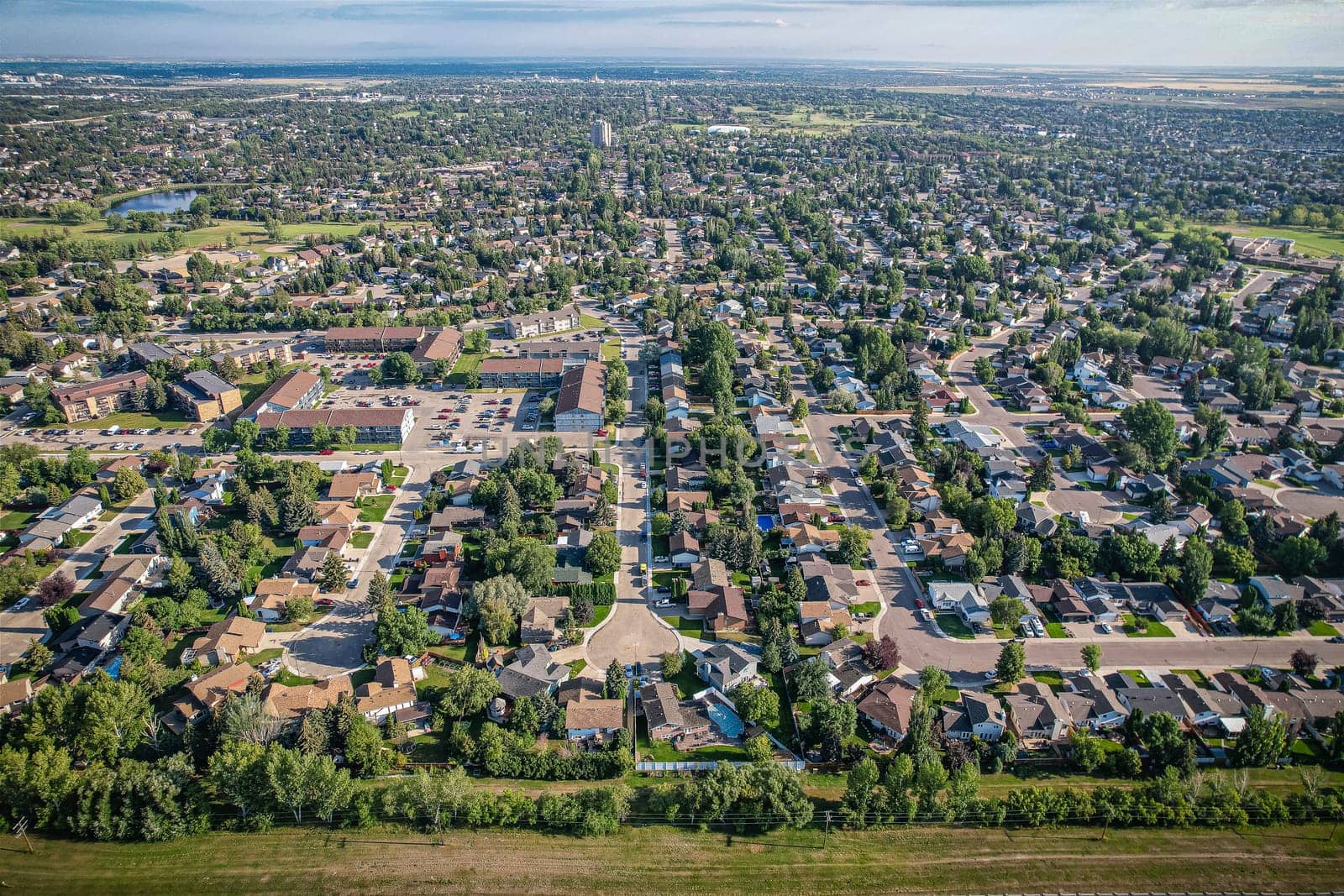 Soaring over Lakeview in Saskatoon, this bird's-eye capture magnifies the neighborhood's tranquil waters, verdant parks, and the serene rhythm of Saskatchewan living