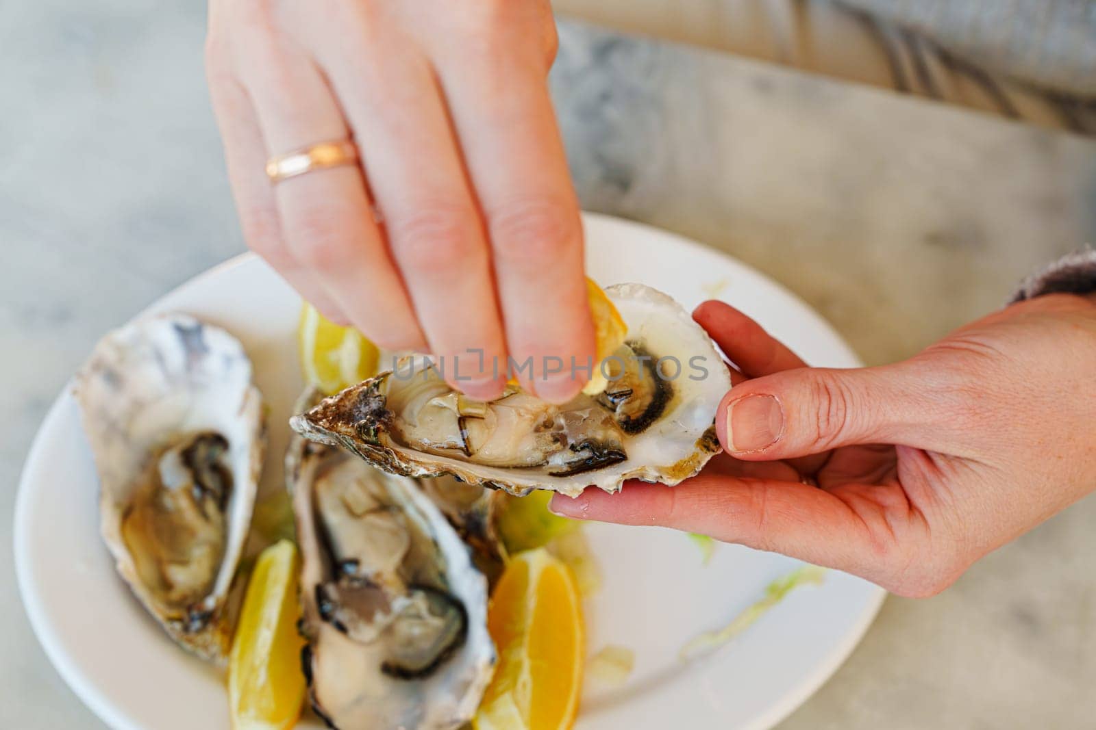 Young woman savoring a gourmet delicacy while dining outdoors, oysters and lemons arranged on a plate with silver utensils