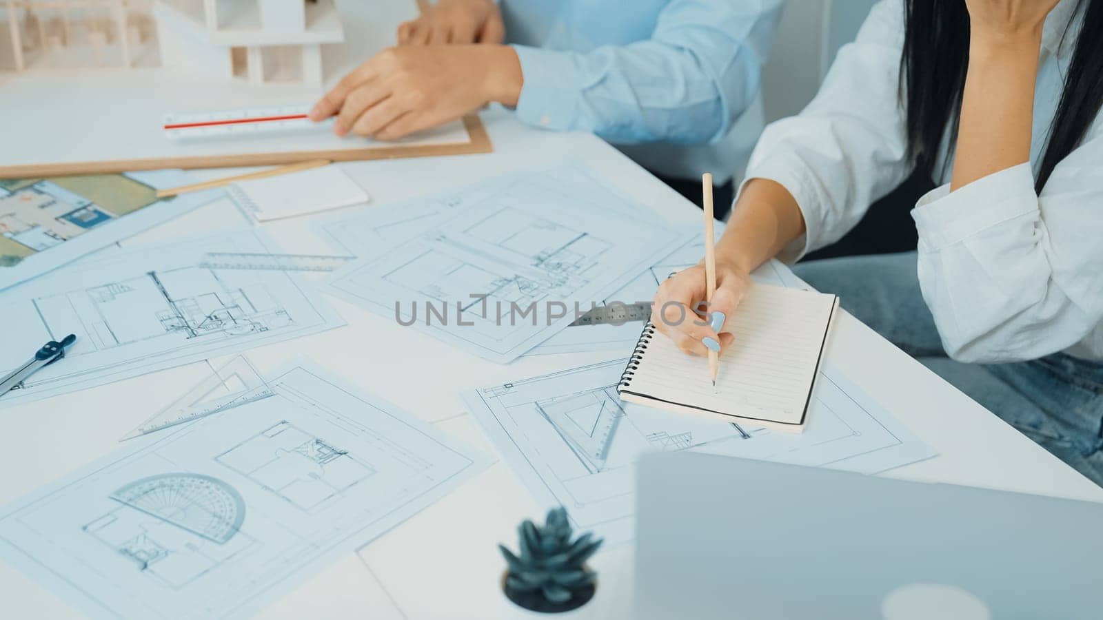 Professional engineer measures house model while skilled designer writes down in blueprint. Work together, collaboration, cooperate. Creative design and team working concept. Closeup. Immaculate