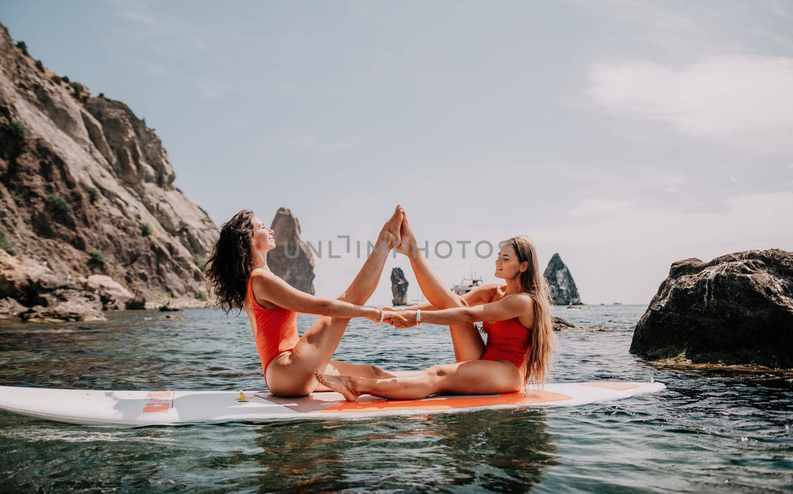 Woman sup yoga. Middle age sporty woman practising yoga pilates on paddle sup surfboard. Female stretching doing workout on sea water. Modern individual hipster outdoor summer sport activity