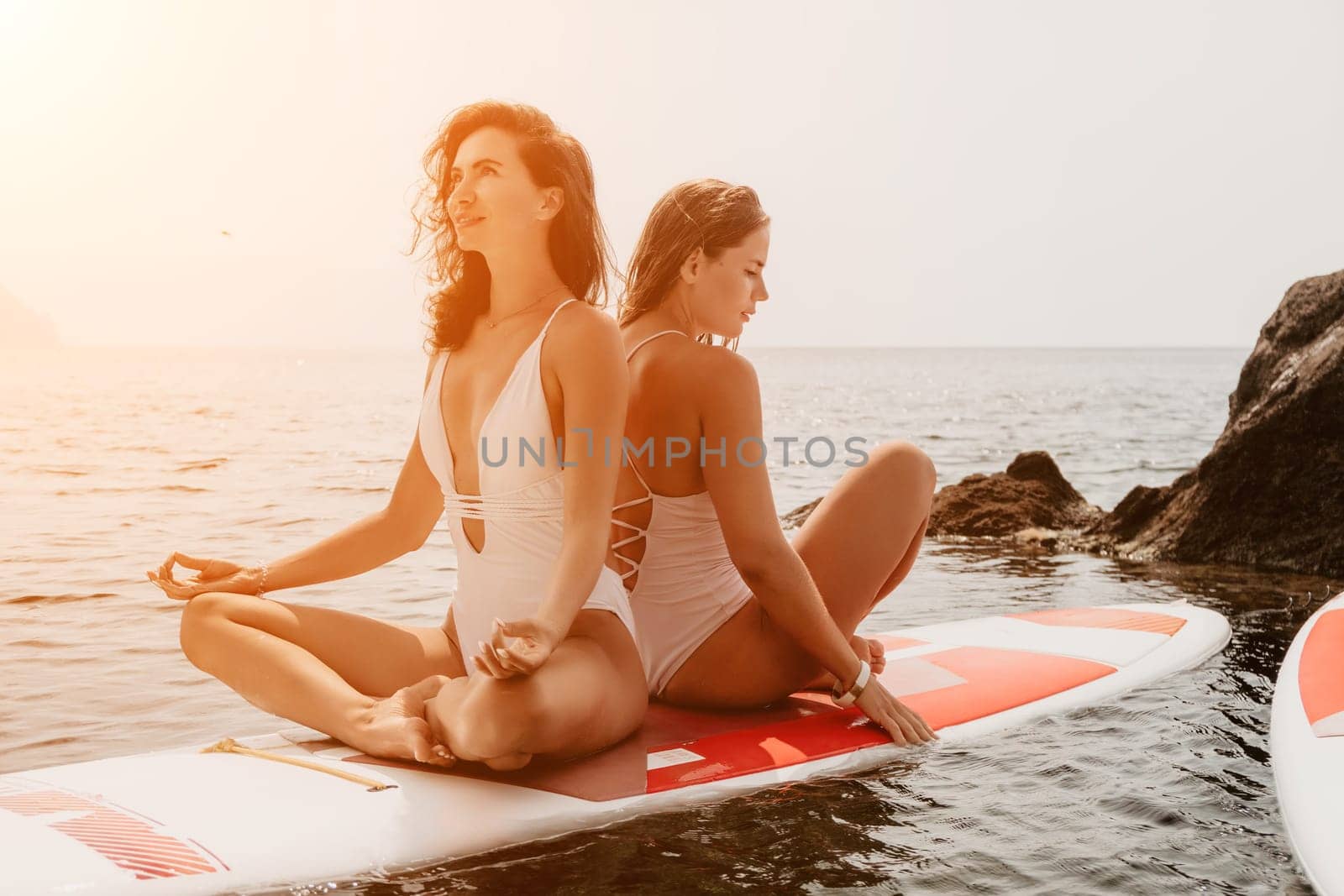 Woman sup yoga. Happy sporty woman practising yoga pilates on paddle sup surfboard. Female stretching doing workout on sea water. Modern individual female hipster outdoor summer sport activity. by panophotograph