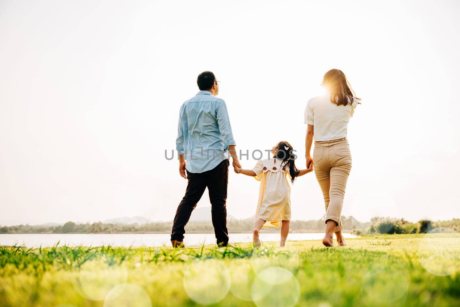 Happy Japanese family walking together in a scenic garden, with a beautiful nature backdrop and the sun shining, enjoying quality time outdoors, Family care, back view