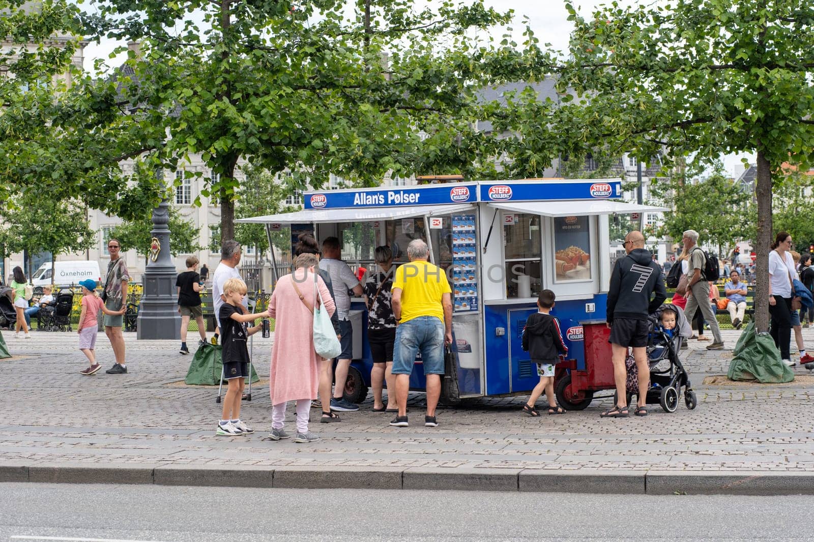 Copenhagen, Denmark - July 11, 2022: Customers at a traditional hot dog cart in the city center.