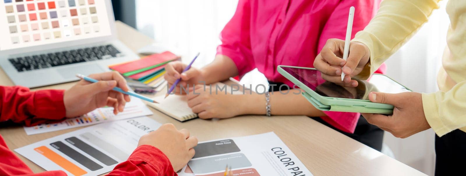 Professional architect designer team brainstorm about color selection while skilled interior design using tablet displayed color palette with color palette document scatter around. Variegated.