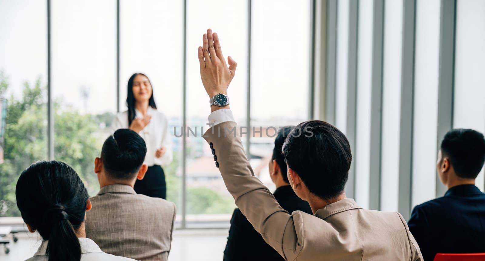 Active participation in a conference seminar classroom, with a large group raising hands. The answers lie within the engaged audience, signifying collaborative learning. by Sorapop