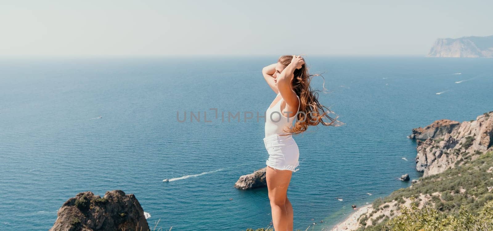 Woman summer travel sea. Happy tourist enjoy taking picture outdoors for memories. Woman traveler posing over sea bay surrounded by volcanic mountains, sharing travel adventure journey by panophotograph