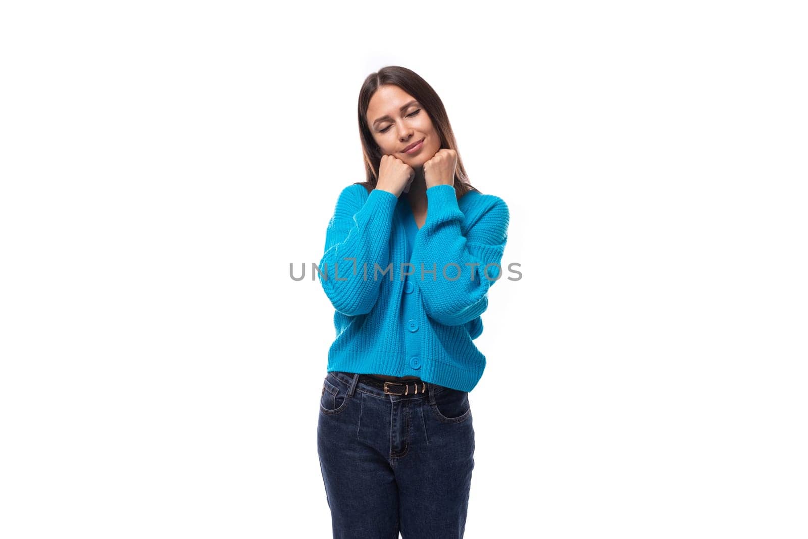 young slender well-groomed European brunette woman dressed in a blue cardigan on a white background with copy space.