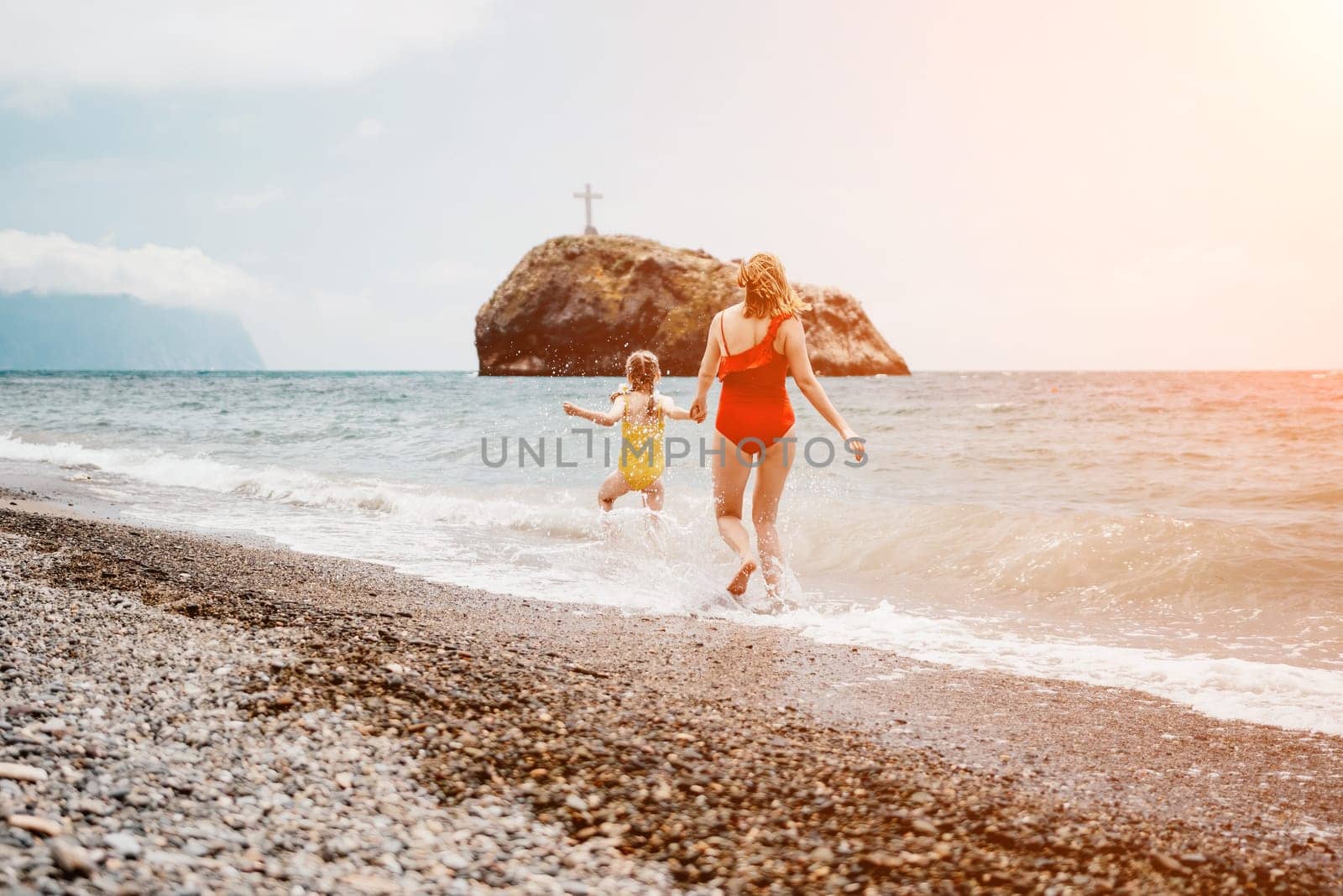 Happy loving family mother and daughter having fun together on the beach. Mum playing with her kid in holiday vacation next to the ocean - Family lifestyle and love concept.