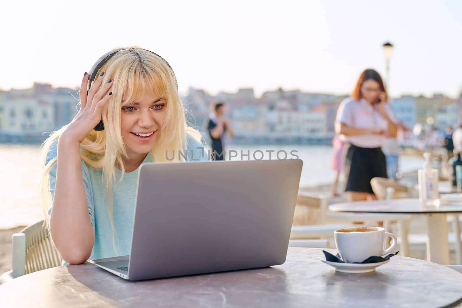 Smiling beautiful teenage girl in headphones looking into laptop by VH-studio