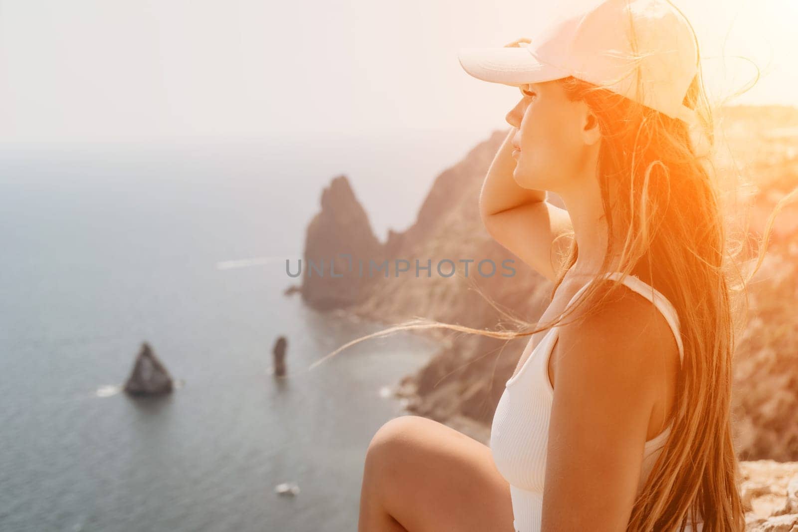 Woman travel sea. Young Happy woman in a long red dress posing on a beach near the sea on background of volcanic rocks, like in Iceland, sharing travel adventure journey