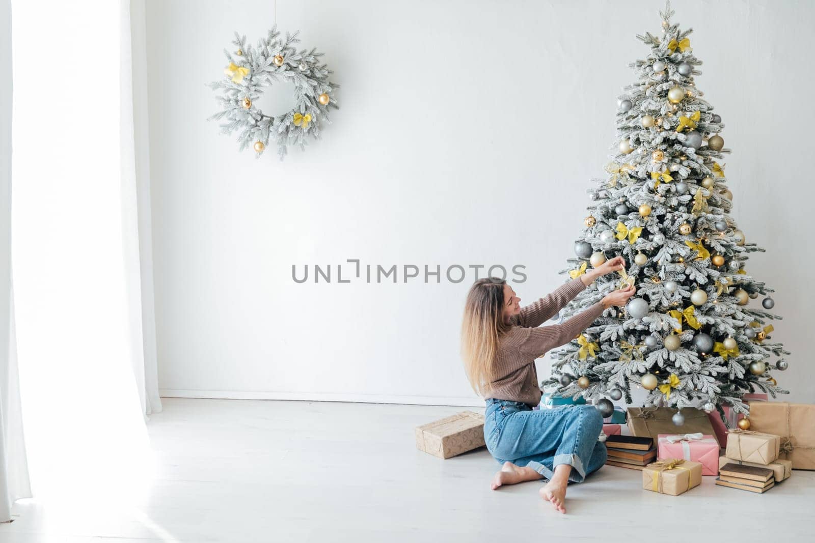 Woman decorating christmas tree with gifts by Simakov